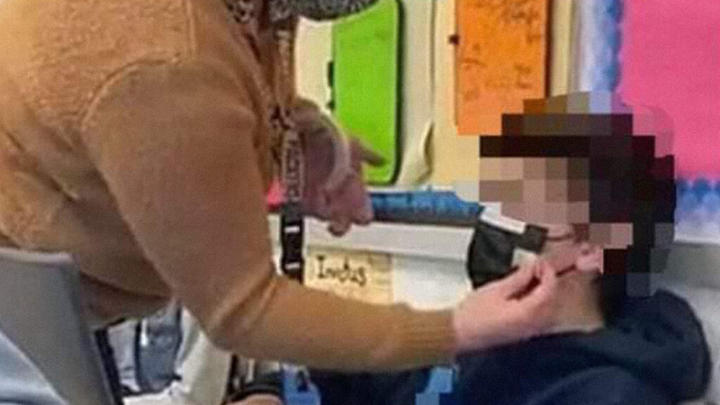 Imagen de una maestra fijando con cinta adhesiva la mascarilla a un estudiante desata la polémica en EE.UU.