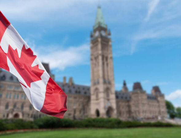 Canadian_flag_waving_with_Parliament_Buildings_hill_in_the_background_Ottawa_Ontario__Canada-810x500