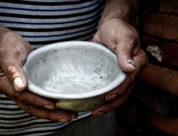 The poor old man's hands hold an empty bowl. The concept of hunger or poverty. Selective focus. Poverty in retirement. Homeless. Alms